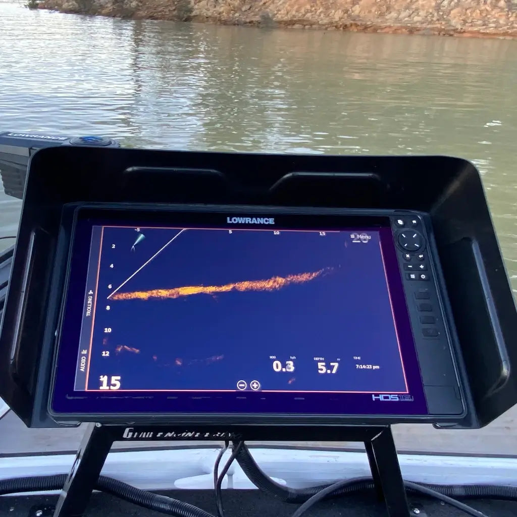 BerleyPro visor shading a fish finder screen on a boat console, sonar trace visible with open water behind