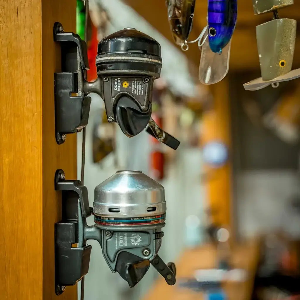 Two spinning reels docked on a timber cupboard door with lures hanging behind