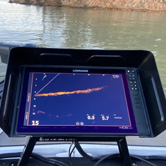 BerleyPro visor shading a fish finder screen on a boat console, sonar trace visible with open water behind