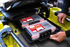 Hands sliding the loaded bottom drawer out of the hatch of a yellow Hobie Outback