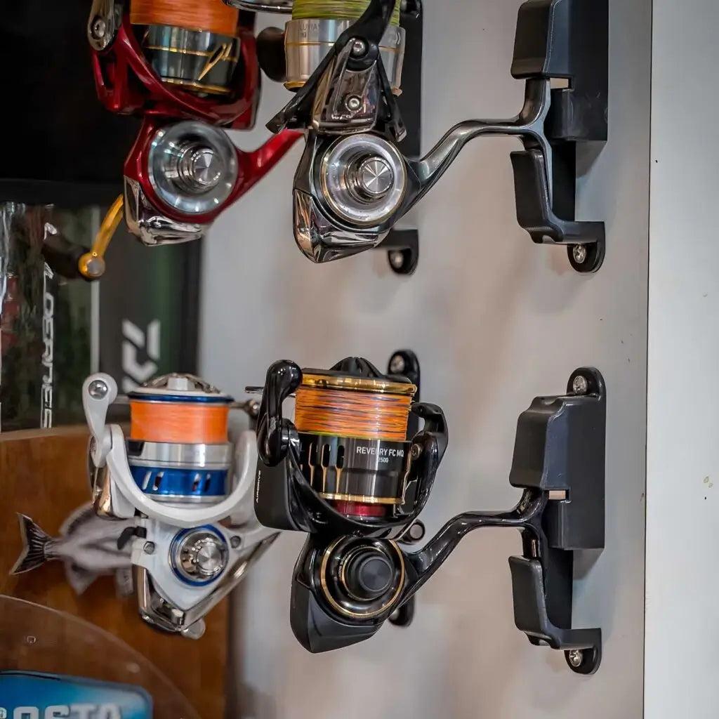 Wall of spinning reels stored on Reel Docks in a garage with rods stacked behind