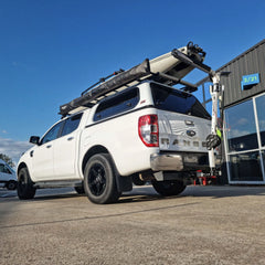BerleyPro Kayak loaded onto a white ute roof rack using the Will-I loader arm outside a workshop