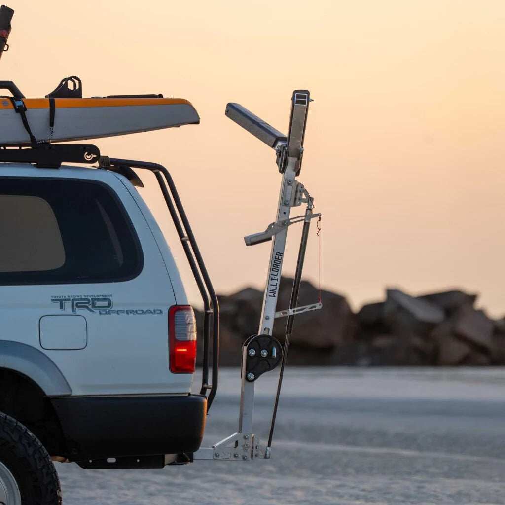 Stainless Will-I kayak loader arm swung down from the roof rack at the rear of a white 4WD